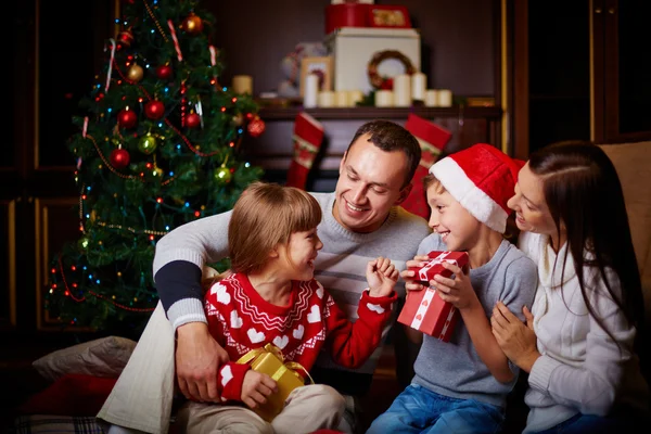 Family exchanging Christmas gifts near a decorated tree in a cozy living room